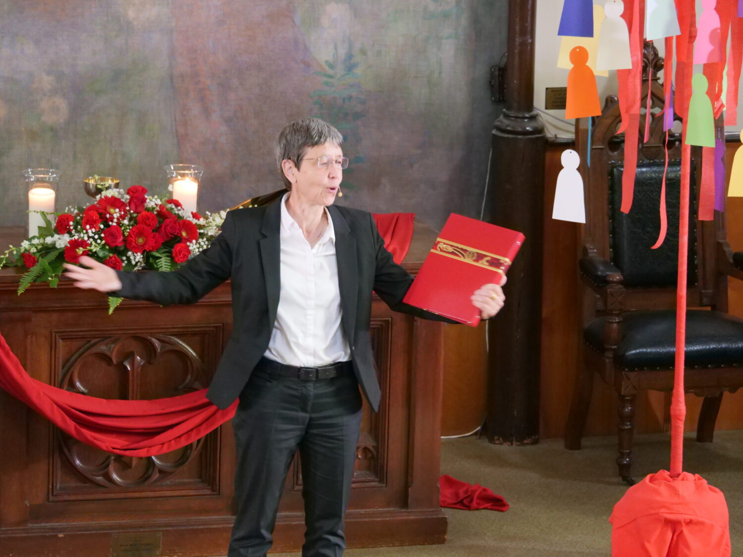 Pastor Daniela Mertz standing at the alter with a red book in her hand
