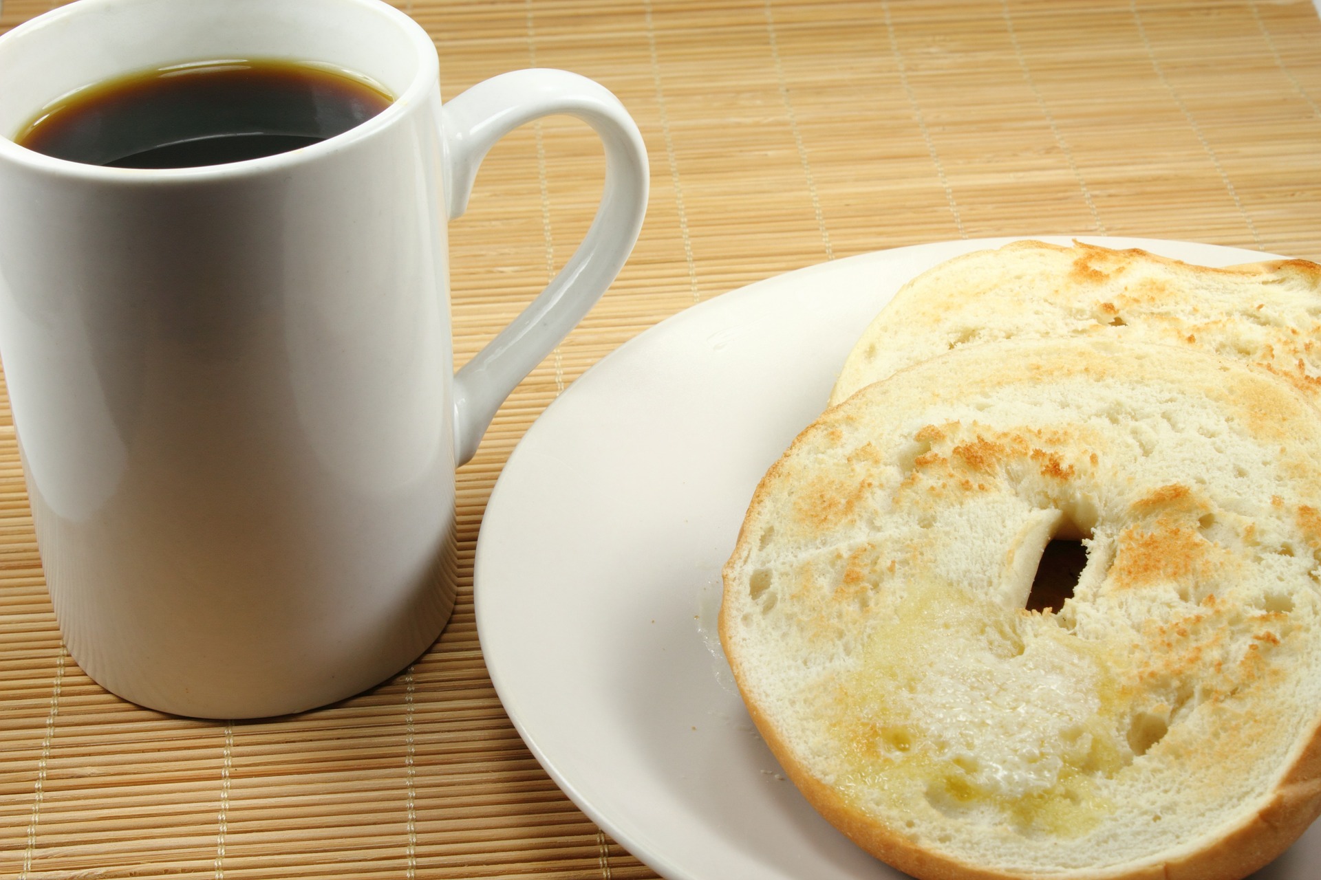 a mug with coffee and a toasted bagel on a plate