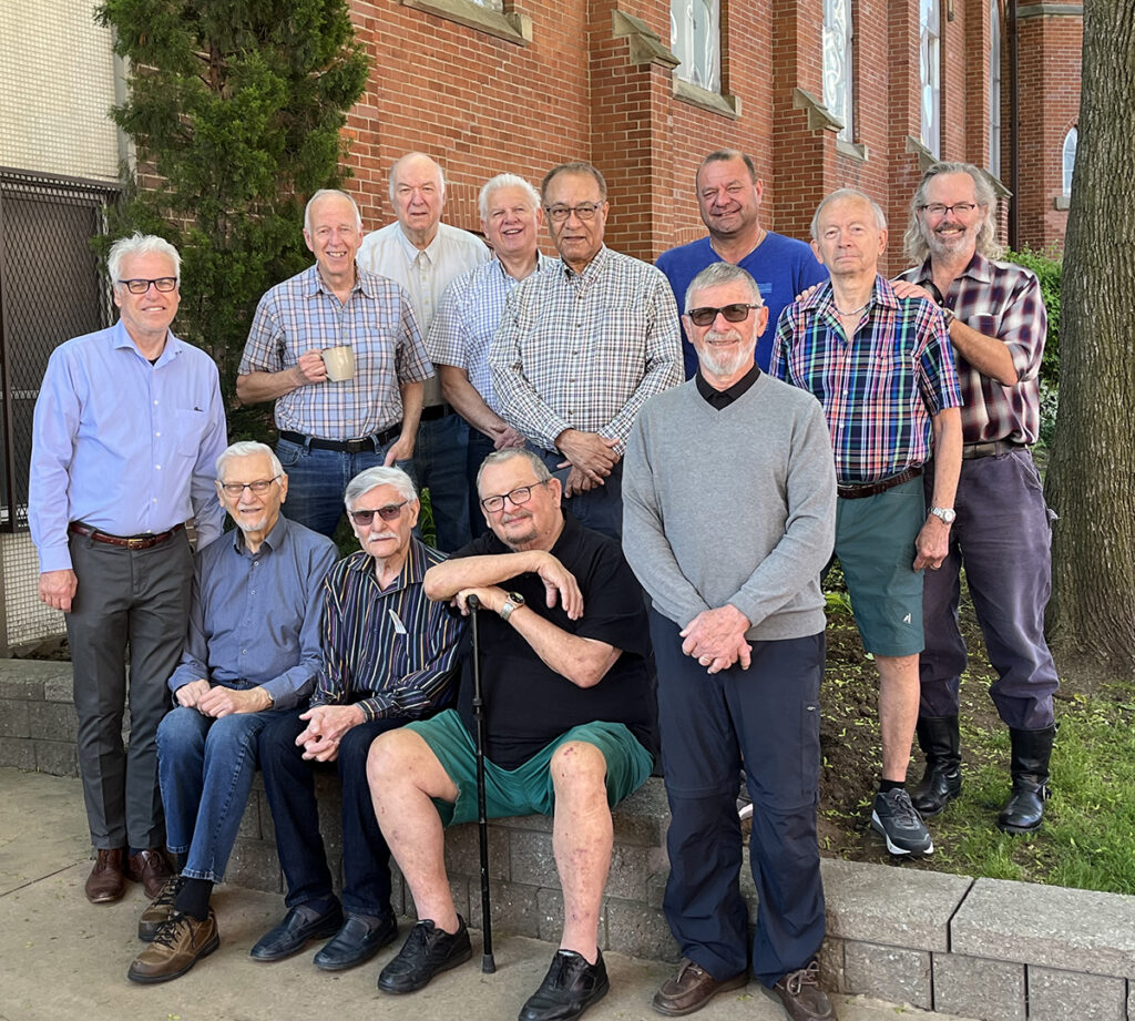a group of men that belong to the the Men's breakfast group standing in front of Trinity Lutheran church