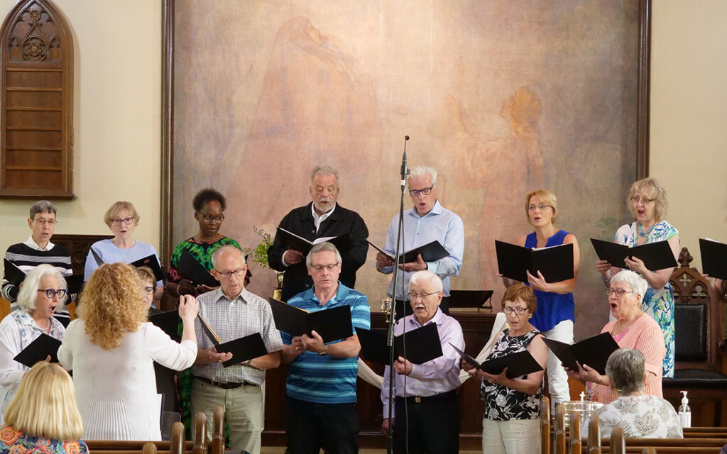 the choir members singing at the front of Trinity Lutheran church with Heide leading
