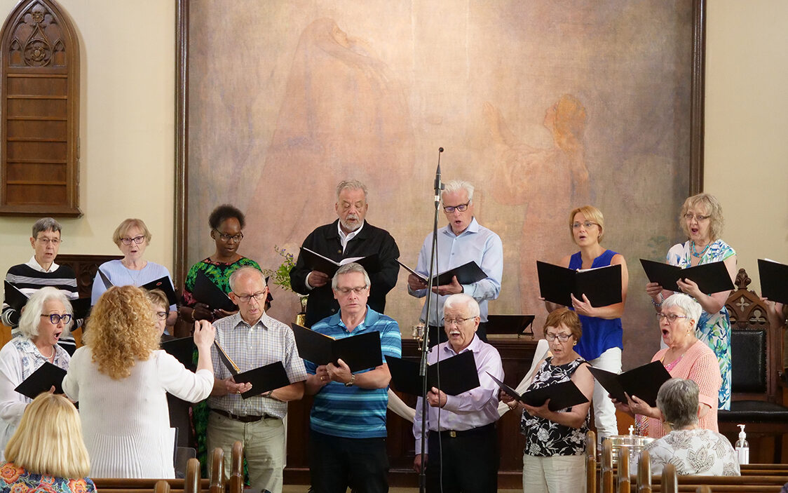 the choir members singing at the front of Trinity Lutheran church with Heide leading
