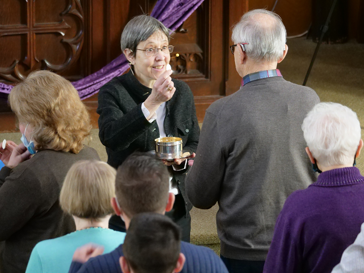 Sunday worship service with Pastor Dani offering communion to parishioners at the front of the church