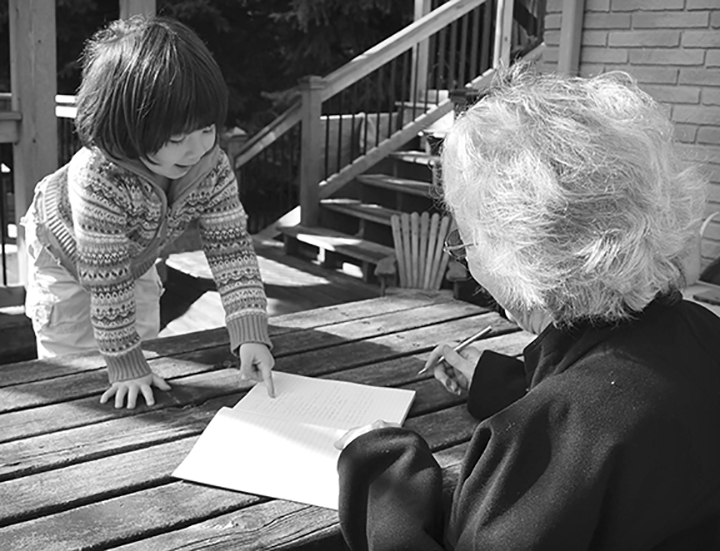 a black and white photo of a young girl and an older woman reading a book together