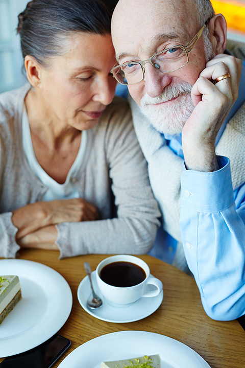a photo of a man and a women sitting very close together with coffee