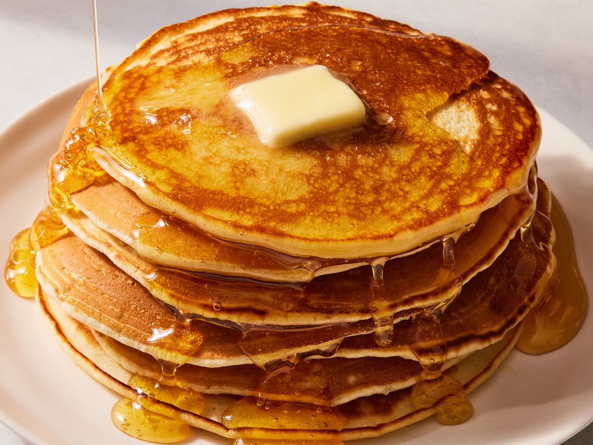 a photo of a stack of pancakes with butter and syrup on top