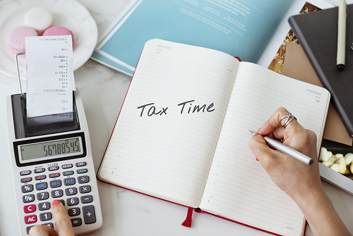 a photo of a calculator and a note book with tax time written in it