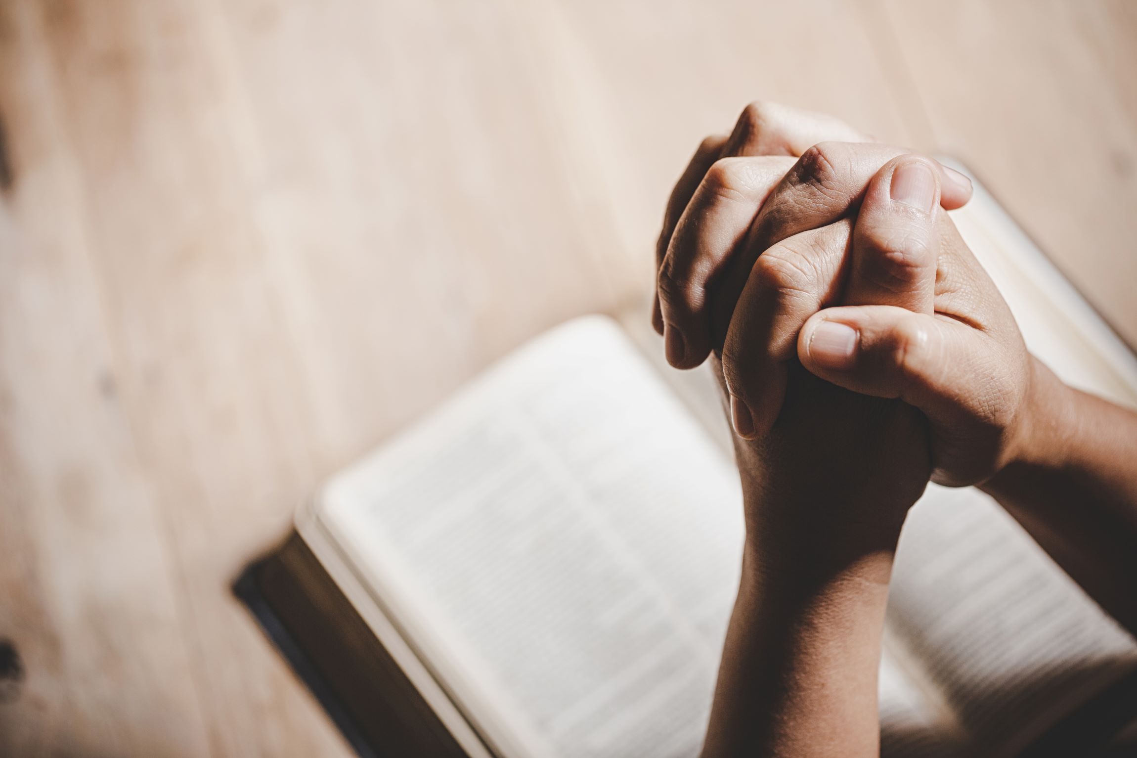 a photo of hands folded together over a bible