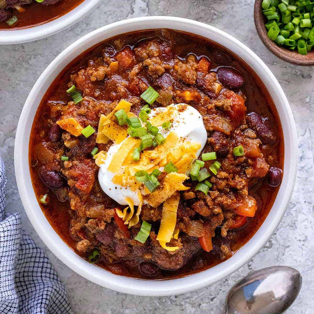 a photo of a bowl of chili topped with cheese and sour cream