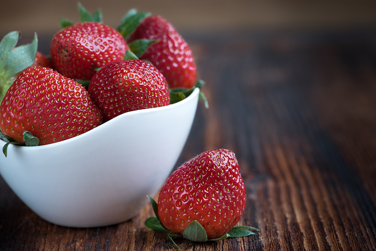 a white bowl with ripe strawberries