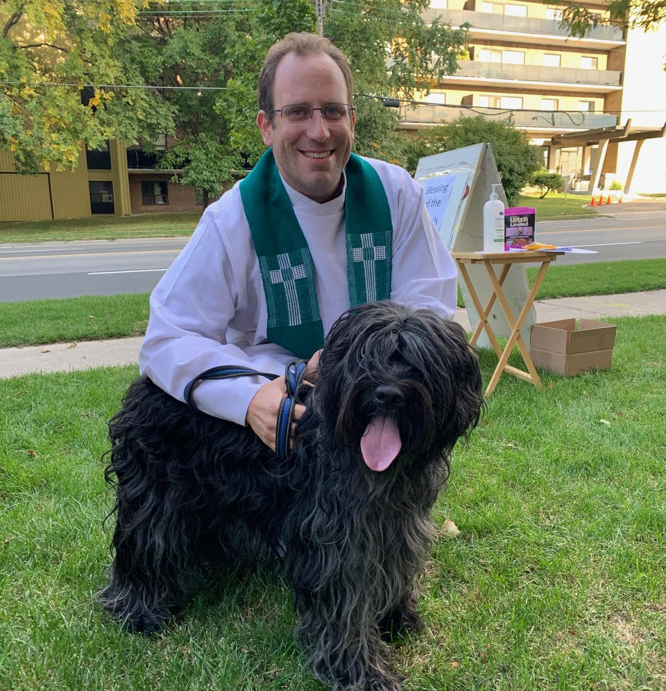 Pastor Jordan Smith beside a black longhaired dog