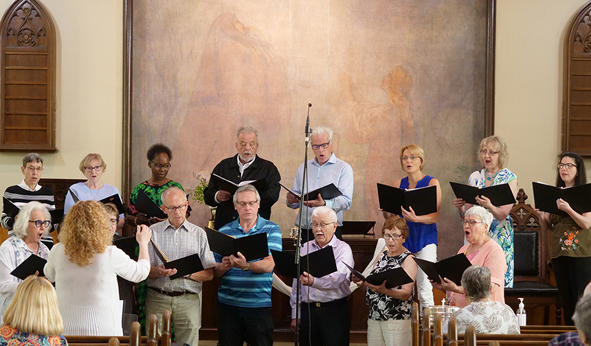 the choir members singing at the front of Trinity Lutheran church with Heide leading