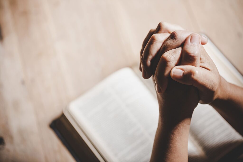 hands clasped together overtop of a bible