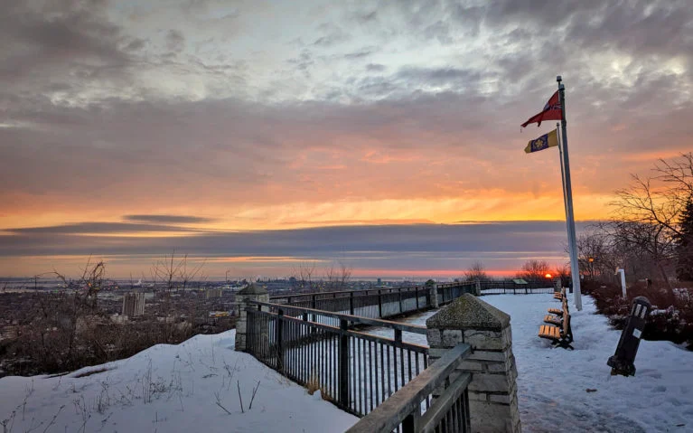 Sam Lawrence park in winter with two flags flying, overlooking the city of Hamilton