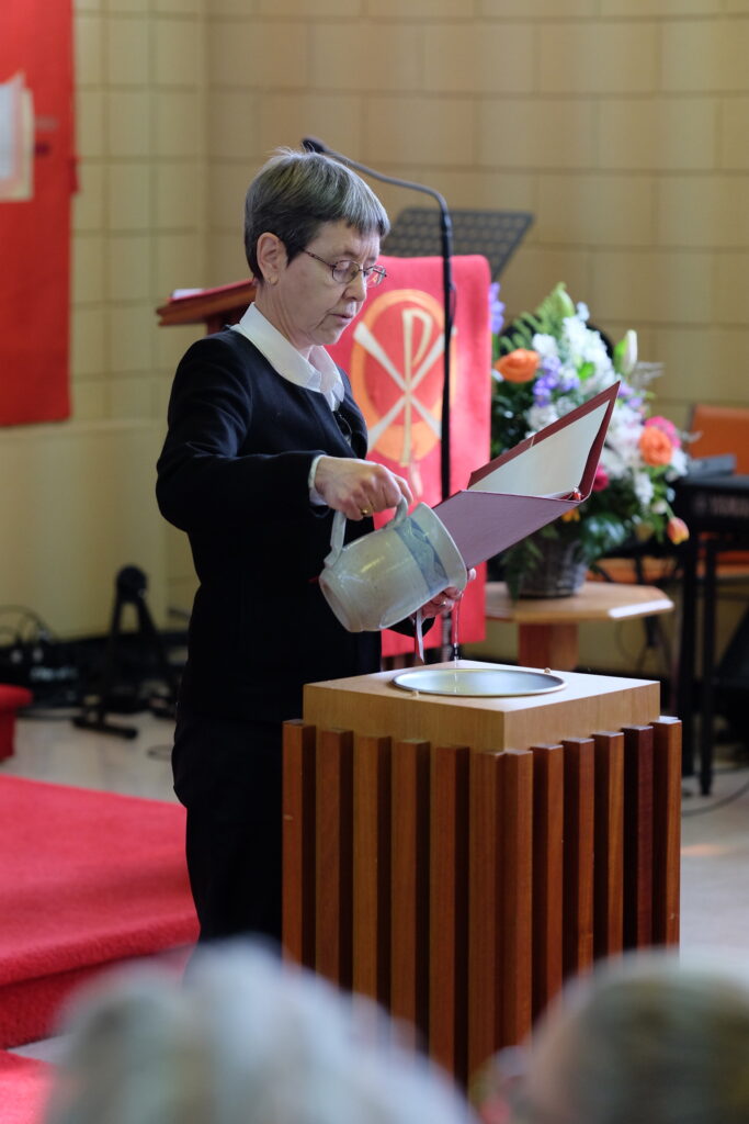 Pastor Dani pouring water from jug at confirmation