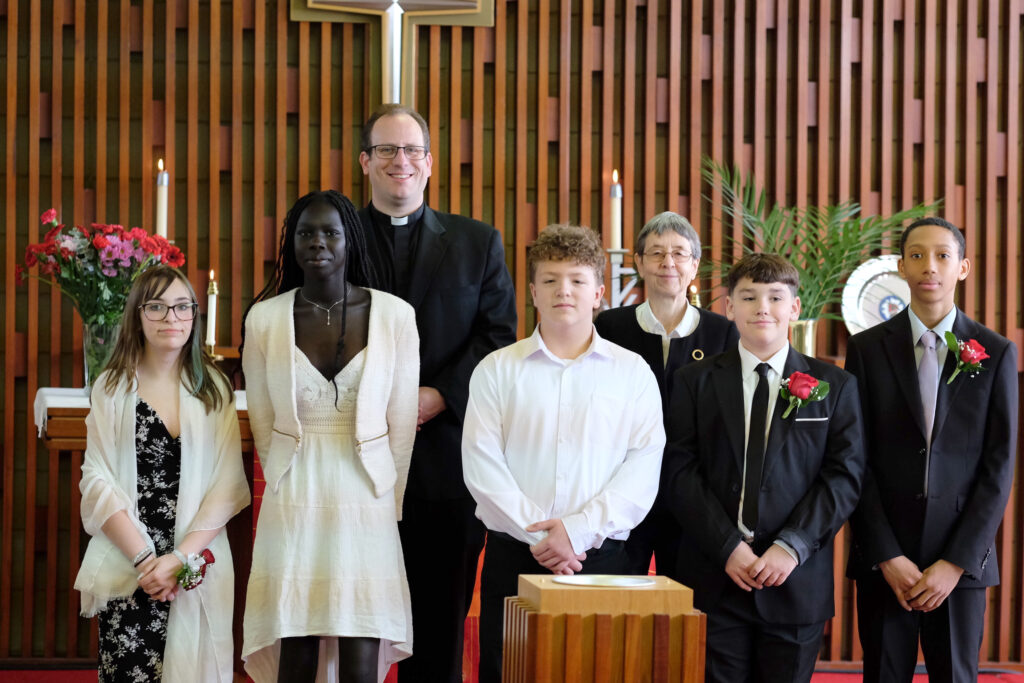 a group of young people and the pastors at the front of the church alter smiling