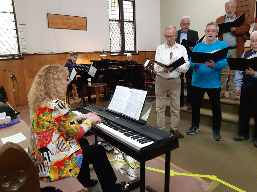 Heide playing piano and choir members sings