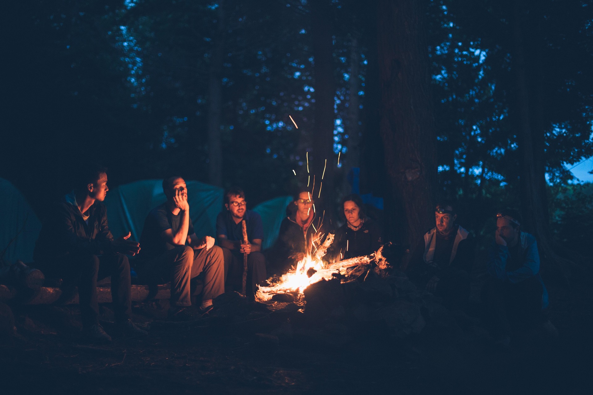 people sitting around a night time bonfire